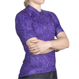 Person wearing a purple cycling jersey with floral pattern on a gray background