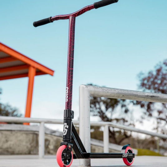 Kids Pro Scooter leaning against railing at a skatepark.